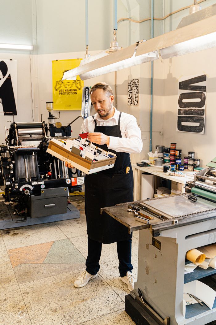 about-us-02 Adult man examining prints in an industrial workshop, highlighting craftsmanship.