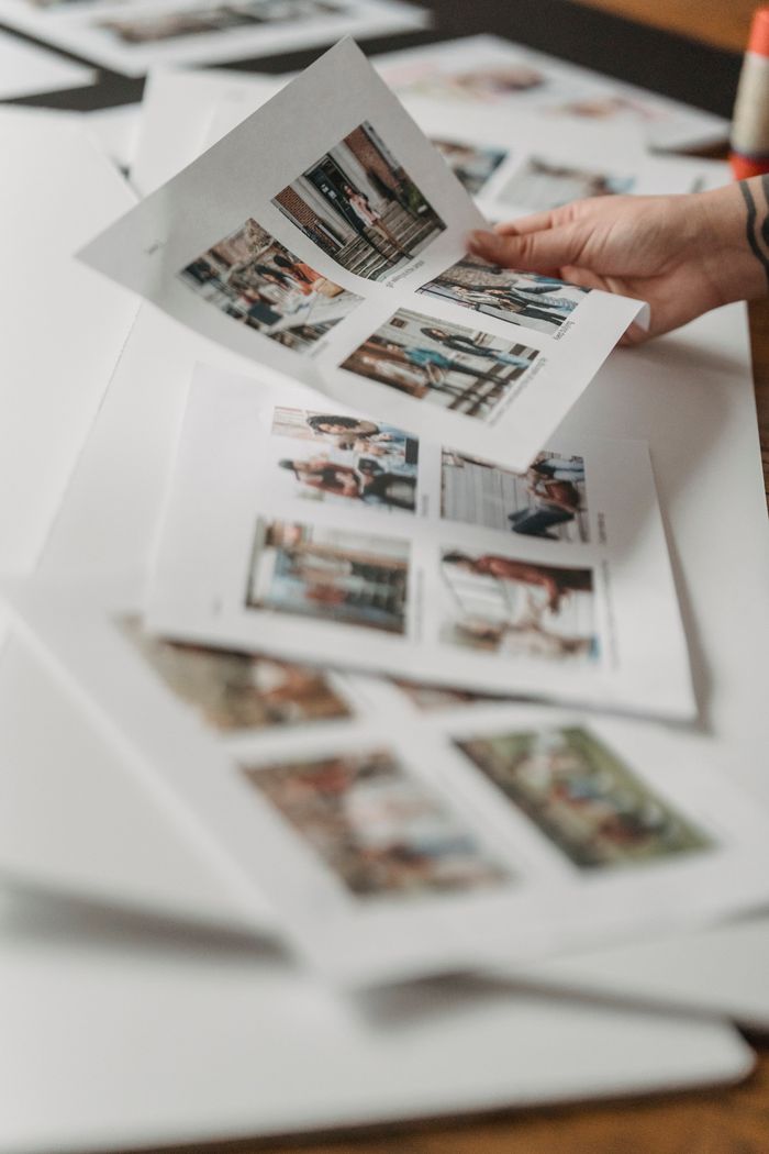 about-us-01 Crop anonymous person looking through printed photos scattered on floor in light room